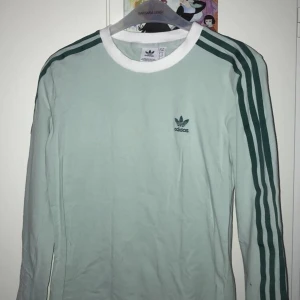 trendig Adidas långärmad tröja - älskar denna tröja, speciellt färgen och tyget som är väldigt mjukt, men använder inte tillräckligt. har använt handfull av gånger. ser skrynklig ut på bilden men det är den inte !                 priset är exklusive frakt, kan även mötas upp i Uppsala ❣️.  stor i storleken, passar mig som är strl. 36/38