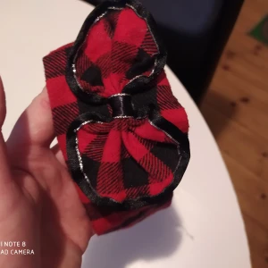 Juligt hårband 2-4 år svart/rött rutigt - Fint skick! Resår bak.  Djur och rökfritt hem. Samfraktar gärna,kika in mina övriga annonser! Frakt tillkommer på 11 kr.