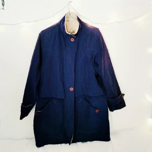  - Marinblå vår/höstjacka i mjukt, nästan sammetsliknande material. Lila knappar (vet ej varför de ser röda ut på bilden?), dragkedja och beige, tunnt foder.