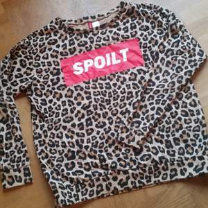 Leopardmönstrad tröja med tryck på framsidan.