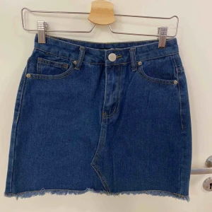 Jeanskjol - Jeans kjol med hällor upptill, fickor både fram och bak, fransar längst ner samt knapp o dragkedja som öppning. Aldrig använd 