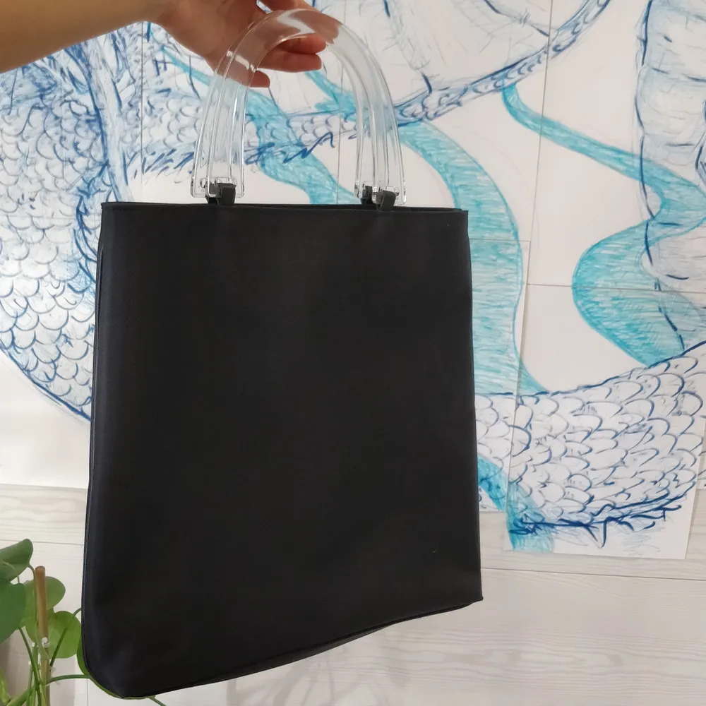 Y2k svart handväska med genomskinliga handtag. Köptes på secondhand och kommer tyvärr inte till användning. Jättebra skick. (Frakt ingår) . Väskor.