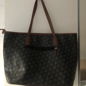 Brun väska med tryck - Säljer min väska från accent (Dondonna). Väl använd men i bra skick! Rymlig väska som fungerar till allt. Skola, gymmet, jobb osv. Pris går att diskutera! Frakt 63kr:)♡  