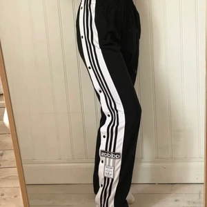 Adidas byxor - Super coola trackpants från adidas. Använda väldigt fåtal gånger. Knappar på sidorna som går att knäppa i princip ända upp. Band i midjan så man kan justera på storleken. Frakt tillkommer🤍 (jag är 165 cm lång💕)