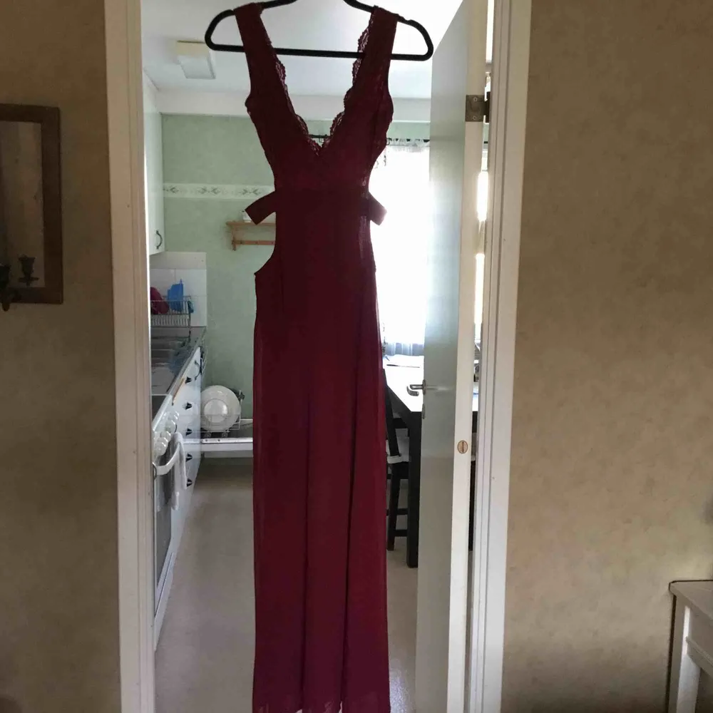 Mycket elegant långklänning i vinröd färg  Långklänning med öppna sidor blixtlås bak spets detaljer  Köparen står för frakt . Klänningar.