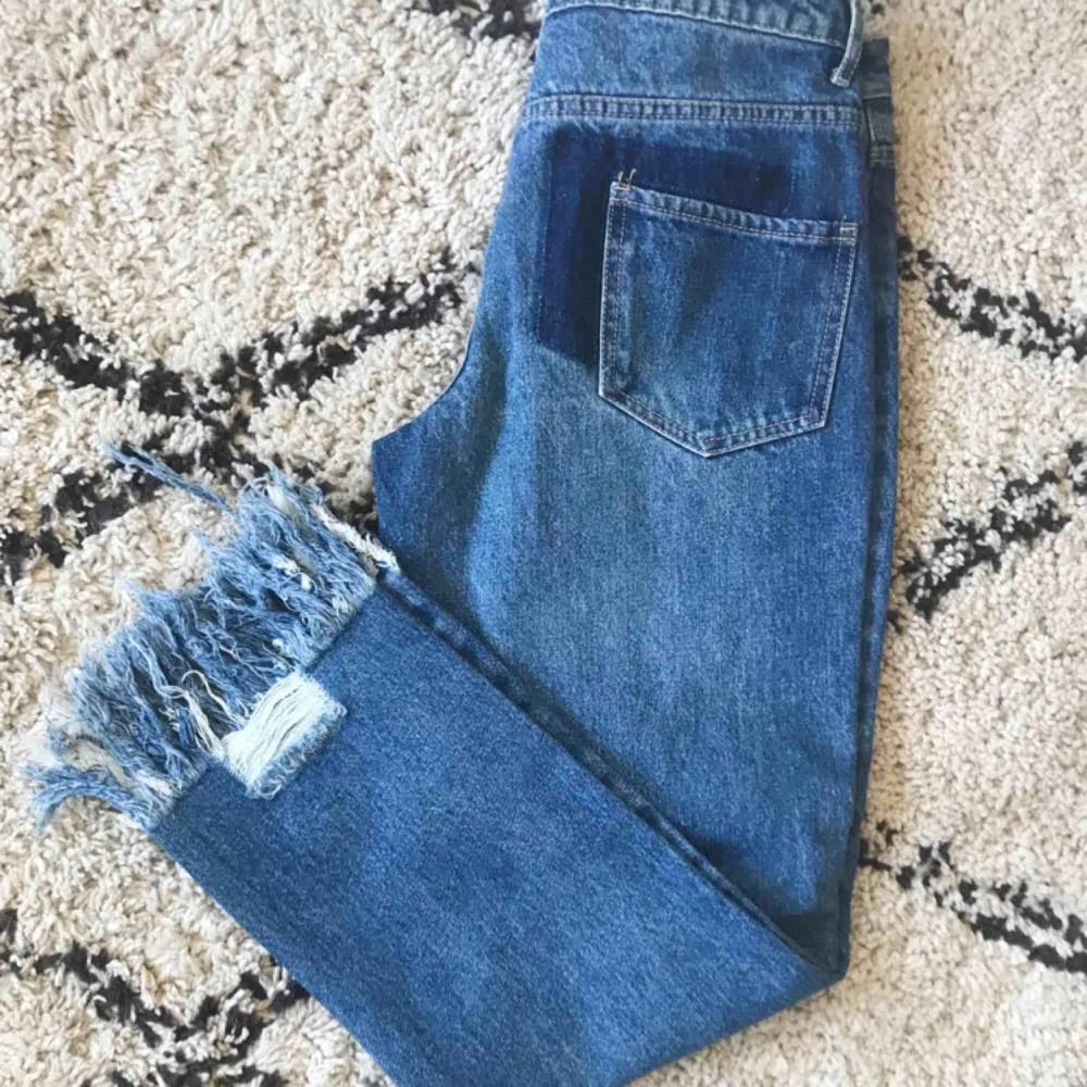 Helt oanvända jeans från Missguided! Håliga med fransar nedtill, mellanblå jeansfärg. Passar bra över lår och höfter på någon som normalt är en medium/26-27a i jeans.. Jeans & Byxor.