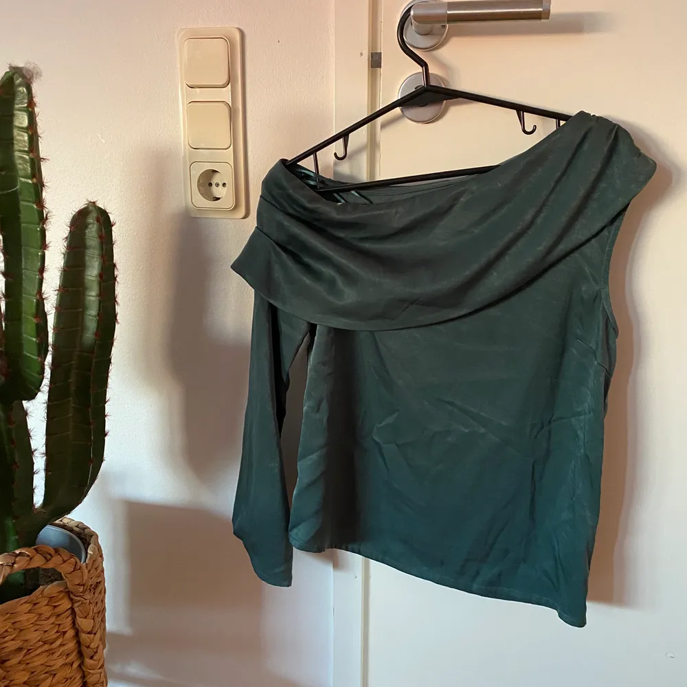 One shoulder satin blouse i färgen grön från en av Hannalicious kollektioner med NA-KD. Strl 34. OBS!!! Fraktkostnad kan ändras vid köp av plagg (beroende på ifall en större påse behövs). Blusar.