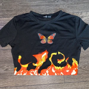 T-shirt med fjäril/eld detaljer, strl xs - Aldrig använd, köpt för ca en månad sen. Tyget är väldigt bra kvalite, mjukt o skön! Kommer ifrån Shein i strl xs 