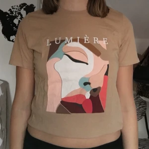 T-shirt med tryck  - Säljer denna t-shirt med lumière text och tryck kommer från Gina tricot. I storlek S✨ (köpare står för frakten, 44kr📦) BETALNING SKER VIA SWISH 