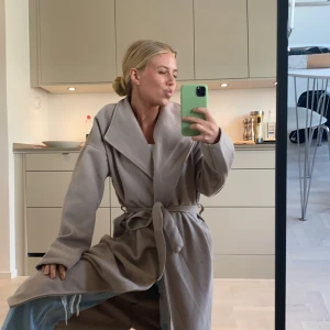 Oanvänd kappa - Beigegrå kappa med prislapp kvar. Frakt tillkommer 63kr. Jag är 1.64 lång.