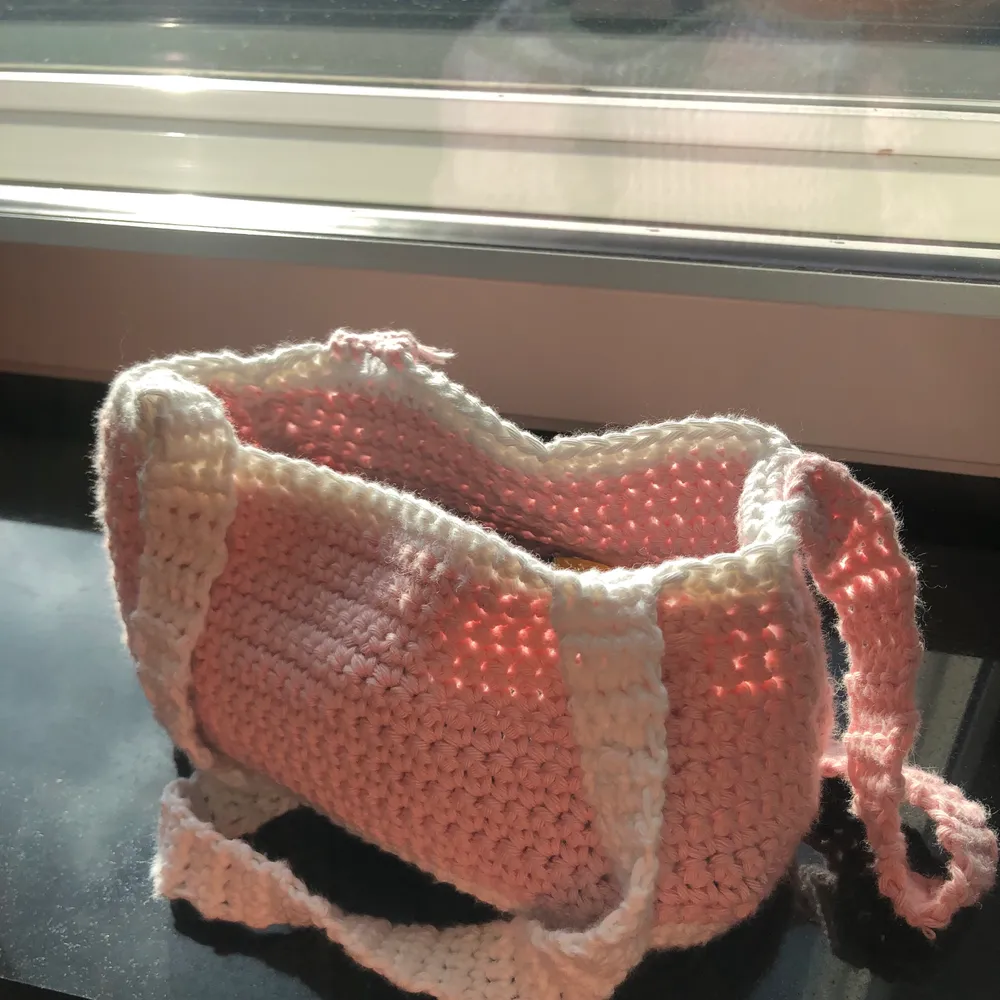 Liten virkad väska i färgerna rosa och vit. Får plats med både telefon oh plånbok.. Väskor.