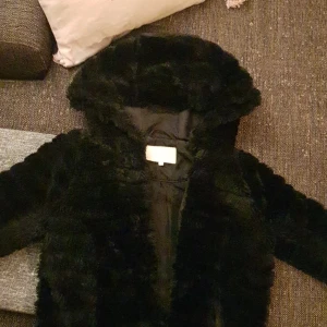 VILA fluffig jacka med stor luva, storlek XS - En svart fluffig jacka i storleken XS men det går även bra till S, anledningen till att jag säljer denna är för att det är för liten storlek för mig då jag har storlek M
