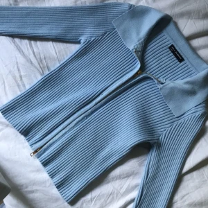Babyblue topp - Ribbad långärmad babyblue topp, med krage och dragkedja i guld som går att dra upp från båda hållen💙! Plagget kommer från ett märke som heter ”Xin yi zu wears”. Använd 1 gång så i jätte bra skick förutom en  liten fläck i armvecket som mestadels syns i blixt, annars jätte fin! Materialet är ganska tjockt och mjukt! 
