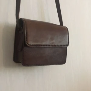  - Bosboom vintage axelremsväska i brunt läder Mått: b14,5 x h11,5 x d6,5 Har fått en fin vintage-slitning i lädret och är fortfarande i mycket fint skick!  Ett fack inuti och ett litet ytterfack under locket finns. Stängs med magnet-lås.  Kan hämtas i Göteborg eller skickas. Köparen står för frakten! 