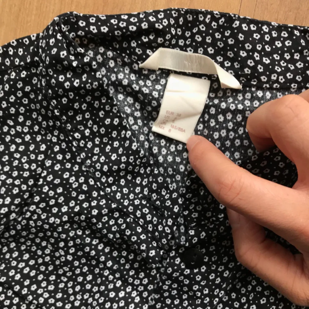 Black cotton shirt with flower motives. It has a mao collar, ruffles front and back, hidden buttons. From H&M, very well maintained quality. Didn’t iron it for picture but super good quality.. Blusar.