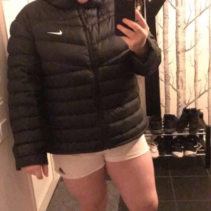 Nike Dunjacka (w Lt Dwn Jkt) - Dunjacka köpt från stadium, nypris 1699:-. Ramlade med moppen och den fick hål, som är lagat, syns på bild 3 (hålet syns inte framifrån). Knappt figursydd så passar både tjej och kille. Går till högstbjudande, ni står för frakten.   