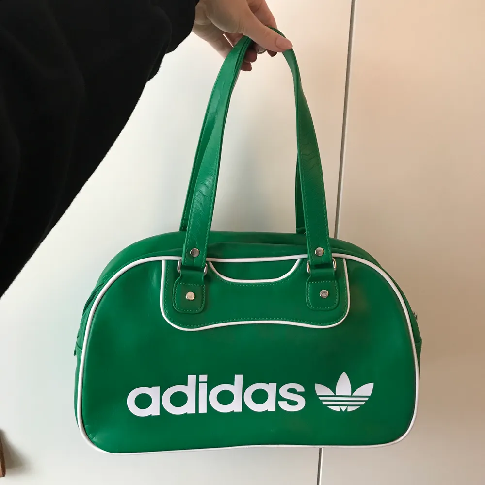 Så snygg grön väska från Adidas (äkta), den är helt oanvänd så den är i nyskick! Mått: längd 37 cm, bredd 13 cm, höjd 22 cm, handtagens längd ca 24 cm. Inuti väskan finns tre fack samt ett fack med dragkedja. Vid frågor är det bara att skicka iväg en kommentar eller meddelande💚. Väskor.
