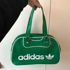 Så snygg grön väska från Adidas (äkta), den är helt oanvänd så den är i nyskick! Mått: längd 37 cm, bredd 13 cm, höjd 22 cm, handtagens längd ca 24 cm. Inuti väskan finns tre fack samt ett fack med dragkedja. Vid frågor är det bara att skicka iväg en kommentar eller meddelande💚