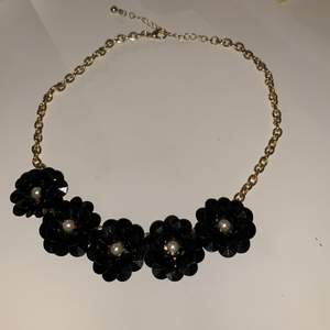 Ett fint halsband i guldfärg och med svarta blommor!