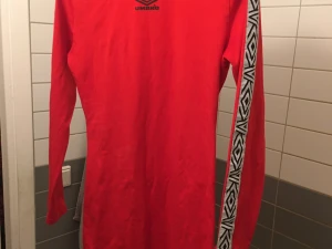 Umbro Bodycon Klänning  - Klänning från Umbro i snygg röd färg. Storlek S men stretchigt tyg. Använd endast ett fåtal gånger.   https://www.asos.com/se/umbro/umbro-bodycon-klanning-med-hog-krage-och-logga-pa-armen/prd/8581166
