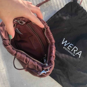  - Axlremsväska i skinn från märket WERA. Väskan försluts med dragkedja och har en justerbar axelrem. Aldrig använd då jag har alldeles för många väskor.   Mått: 23x18x8 cm.