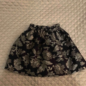  - Marinblå kjol med silvriga blommor. Resår i midjan. Använd 2 gånger. Inköpt på Zara. Köparen står för eventuell frakt. 
