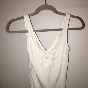  - Vitt linne med snörning. Den är v-ringad både fram och bak. Aldrig använd.