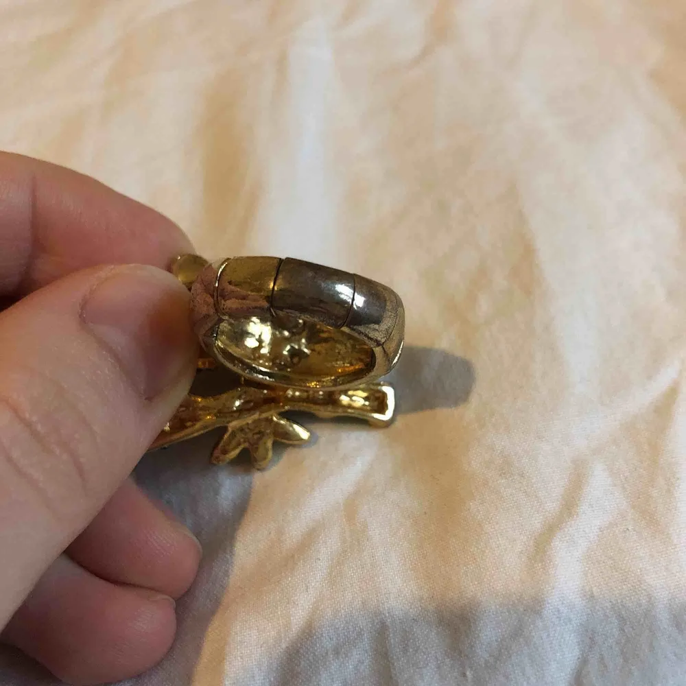 En pandaring med glittriga stenar/pärlor där själva ringen är guldfärgad men lite avskavd färg på undersidan. Annars fint skick.. Accessoarer.