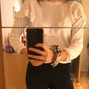  - En sjukt snygg och stilren blus från NA-KD!! Ett väldigt skönt material och fina volanger över bröstet. Tröjan är i en klar vit färg!