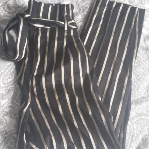  - Trendiga och fina randiga/guldiga byxor med knytskärp. Hög i midjan. Frakt står köpare för!