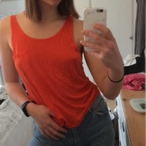 Topp - Orange topp i tunt material, med en liten ficka på vänster bröst