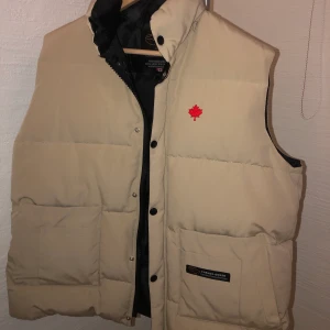 Canada goose väst - Säljer denna snygga beiga vintage canada goose väst, osäker på den är äkta då det är en släcknings gamla, därav priset💛 den är i nyskick då den inte har blivit använd! Står att den är en XXL men jag skulle säga att den sitter Max som en L💛