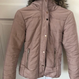 Beige jacka stl 32 - Beige vinterjacka med resår i ryggen för smickrande passform. Midjekort. Nypris 499. Stl 32 men passar även bra på 34