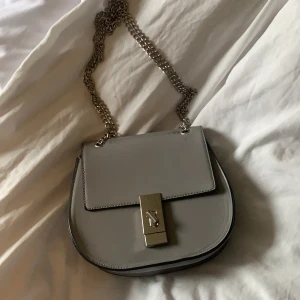 Grå silver väska - Skit snygg grå väska köpt utomlands, silverdetaljer. Man kan välja själv om man vill ha ett eller två ”kedjeband” på axeln. Köpt för 700. Ink frakt