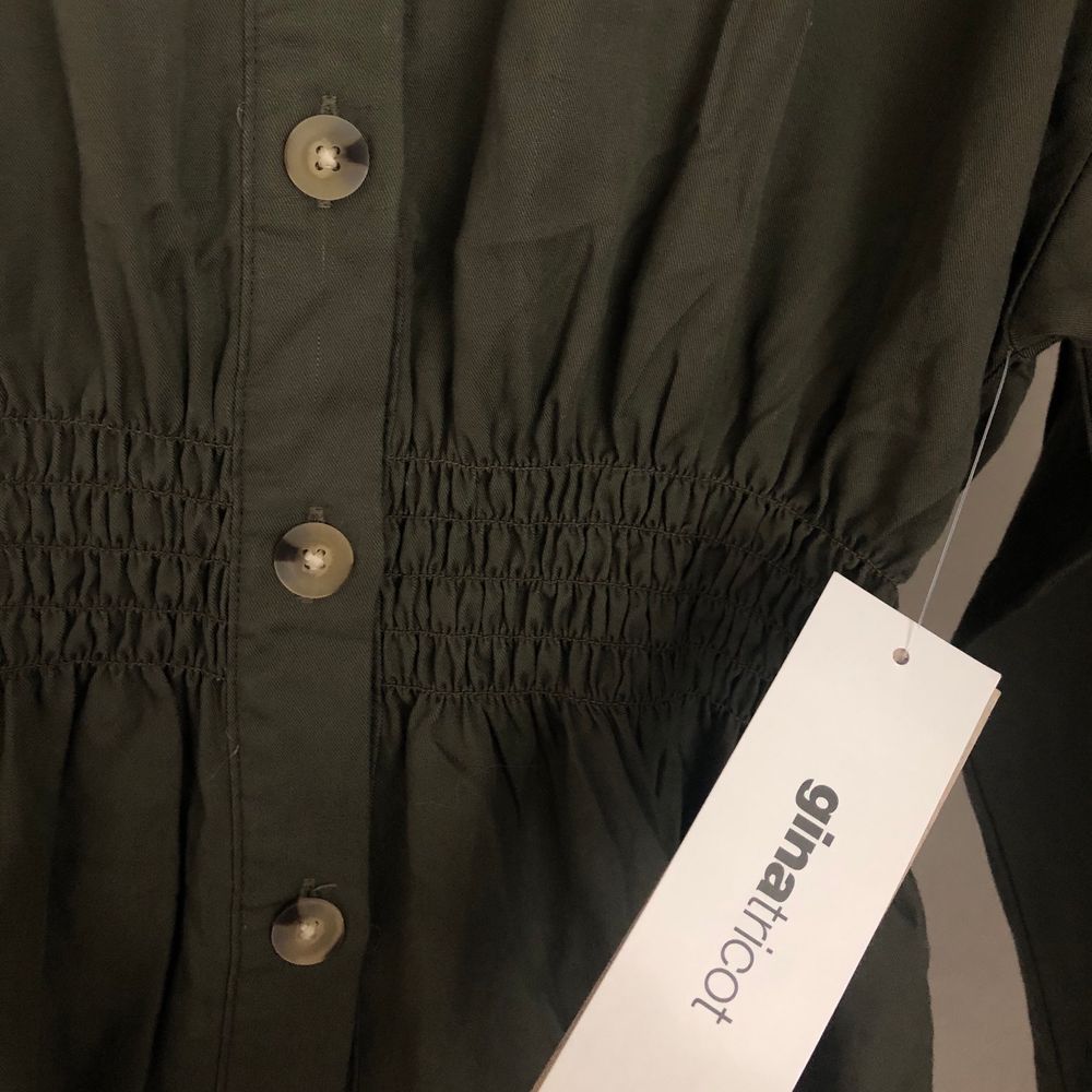En militärgrön skjorta från Gina Tricot med smock detalj i midjan, för att skapa en fin figur. Strl 36. Helt oanvänd med prislapp kvar. Köpt för 350kr men säljer för 250kr + frakt. Önskas fler bilder är det bara att hojta till🌸. Skjortor.