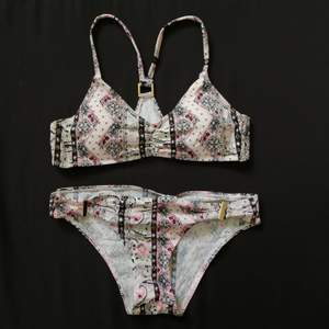 Bikini from Cubus in black/white/pink aztec print. Size S in regular fit. The top has removable padding and no button.
