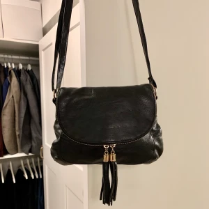 Svart sadelväska  - Svart sadelväska i läder från Don Donna. Använd men i bra skick. Ställbar axelrem. Mått: 29x22 cm. Guldig dragkedja. Skriv för frågor :)