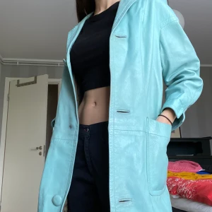 Blå skinnkappa! - Asball vintage babyblå skinnrock/kappa som tyvärr inte används tillräckligt:( Köpt second hand så okänt märke+storlek. Sitter bra på mig som är 172cm. Lite lätt fodrad så perfekt som höst/vår jacka! En knapp saknas men funkar utan. Budgivning från 199kr