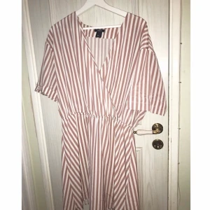 En matt rosa/beige klänning från Lindex - En matt rosa / beige klänning från Lindex gjort i materialet polyester, storlek L. Frakt ingår ej i priset. 