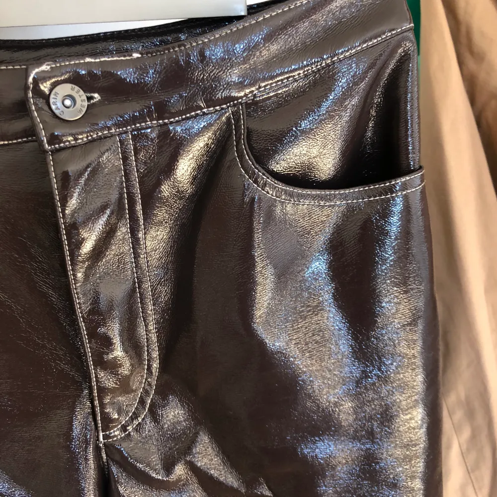 Ett par lackbyxor i mörkbrun/mörklila färg från Carin Wester. Aldrig använda men har dragit av prislappen. Ankellängd.. Jeans & Byxor.