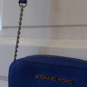 Fin liten blå crossbodyväska med silvriga detaljer från Michael Kors. Självklart äkta, köpt på NK för ca 5 år sedan. Kommer aldrig till användning då den inte är min stil, använd max 3 gånger. Kan mäta hur stor den är om nån önskar.