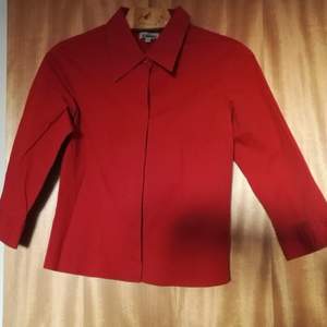 Röd skjorta med lite längre kragsnibbar. Stadigt material och något formsittande. Betalning på Swish helst och frakt tillkommer.