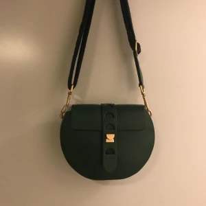  - Handväska från coccinelle. Helt oanvänd! Två axelband att variera med, ett i grönt läder och ett i tyg med mönster. 