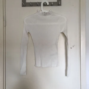  - Söt vit tröja som är oanvänd. Den ser liten ut men är superstretchig. Upptill har den en söt detalj som gör tröjan extra snygg. Passar till vardags och till fest.  Frakt ingår INTE I priset. 