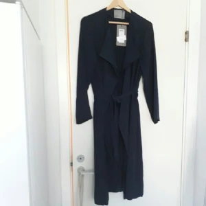  - fin mörkblå trenchcoat, aldrig använd pga fel storlek. Nypris: 399 kr. Hämtas i Ystad eller Malmö ,annars betalar köparen frakten :)