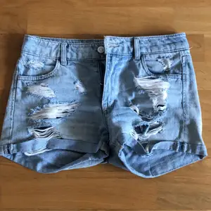 urtvättade jeansshorts med hål på fram och baksida, medium midja