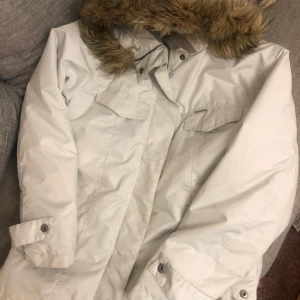 Vinterjacka / Dunjacka från Columbia Strl M - Säljer denna vinterjacka från Columbia! Den är Vit/Beige till färger och har storlek M. Yttermaterialet är gjort av 100% polyester och innanmätet i dun, håret runt luvan är gjort av fejkpäls. Den är varm/vindtät och passar vintrarna i Sverige. Den går att tvätta i maskin och är i perfekt skick.