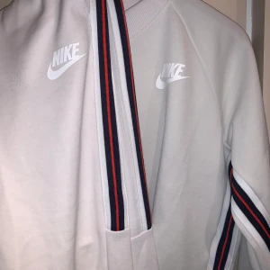 NIKE TRACKSUIT  - En benvit Nike tracksuit med revär på sidan. Nypris tröja 399kr byxa 579kr. Setpris 350kr + frakt