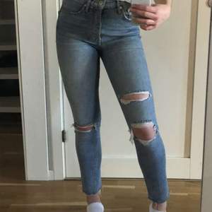 Fina, ljusblåa, highwaisted jeans med hål/slitningar från Gina tricot. Använda men i väldigt fint skick! Innerbenslängden är ca 71 cm. Köparen står för frakt!✨