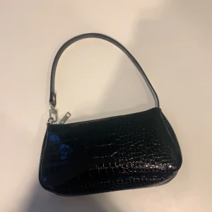 Svart läderväska - En fin väska som passar till alla kön och alla stilar som dessutom är gjord utav läder och silver detaljer. Väskan är ungefär 30 cm och får plats med mycket saker. 